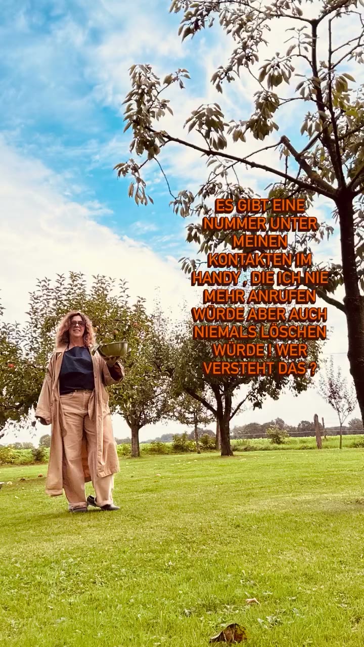 CEE in weiter beiger Hose und dunkelblauer Bluse auf der Obstwiese unter einem Apfelbaum.